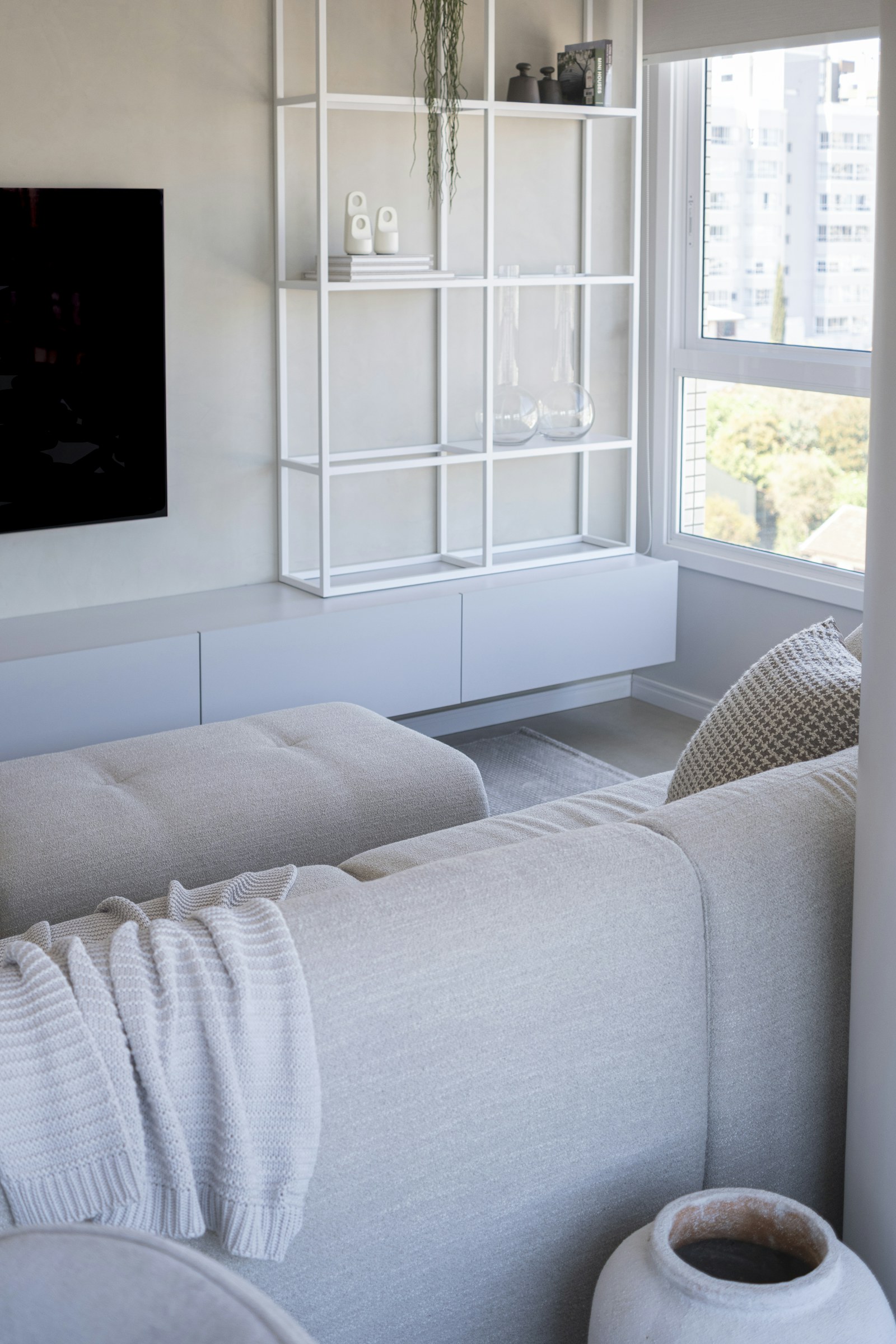 A bright living room with geometric shelves and soft fabric textures